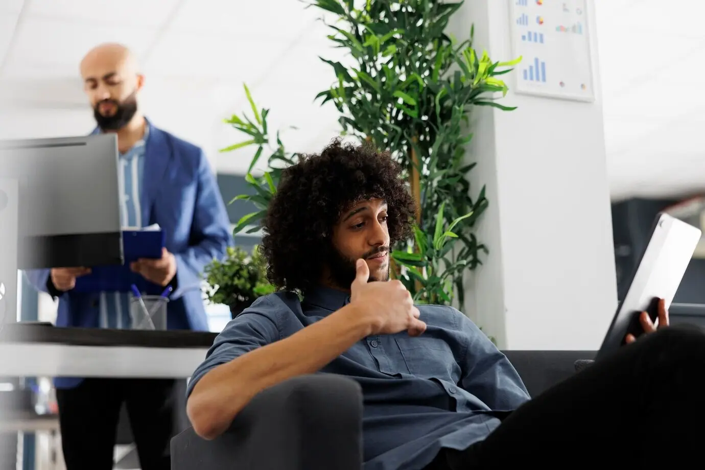 Ein Finanzanalyst eines Unternehmens bespricht in einem Online-Meeting einen Bericht und verwendet dabei ein digitales Tablet. Ein junger arabischer Start-up-Unternehmer unterhält sich während der Arbeit im Büro in einer Videokonferenz mit einem Manager.